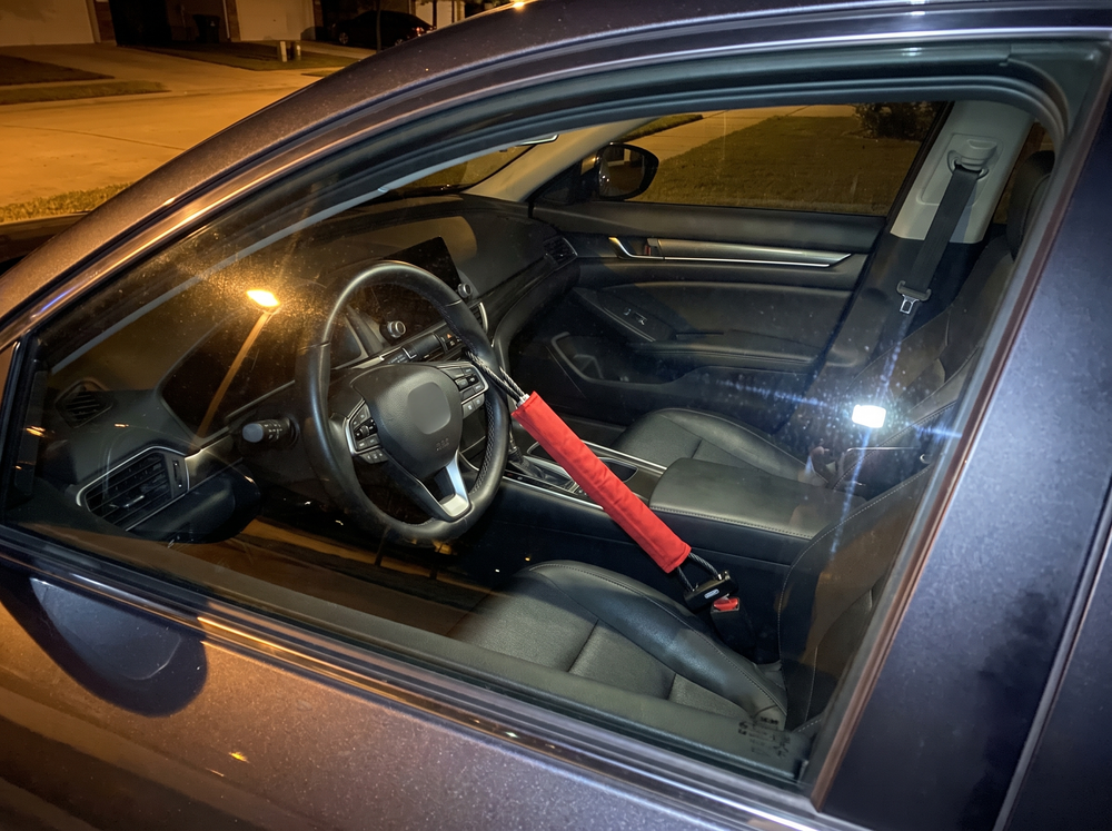 Car at night with a red NoTheft lock from the steering wheel to the seatbelt buckle