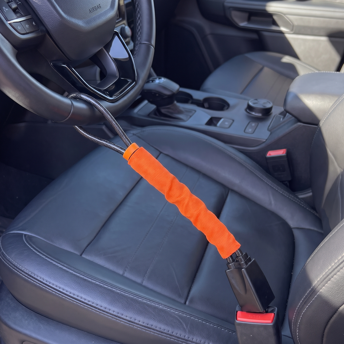 Orange NoTheft lock fitted from the steering wheel to the seatbelt buckle
